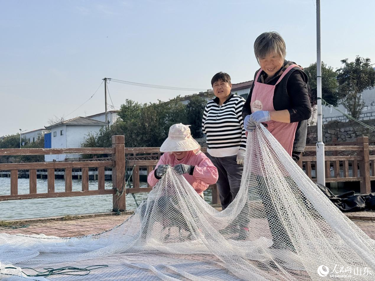 村民脸上洋溢着笑容，正在织捕鱼网箱。人民网 郑昕桥摄